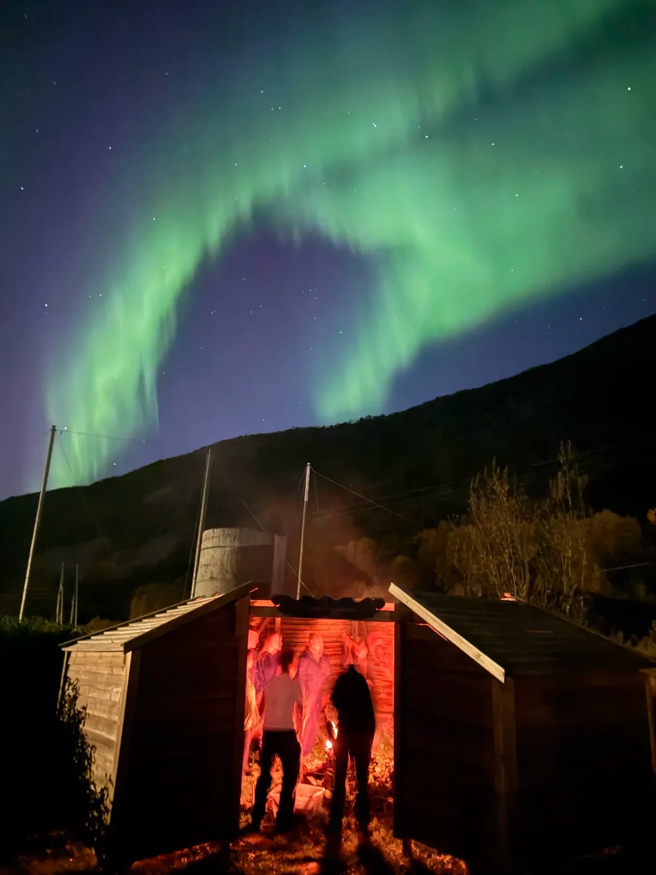 Gruppe i silhuett ved gapahuken under nordlyset