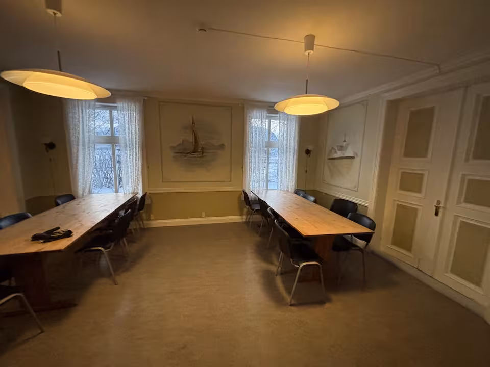 Spisesal med to langbord og maleri av seilskute