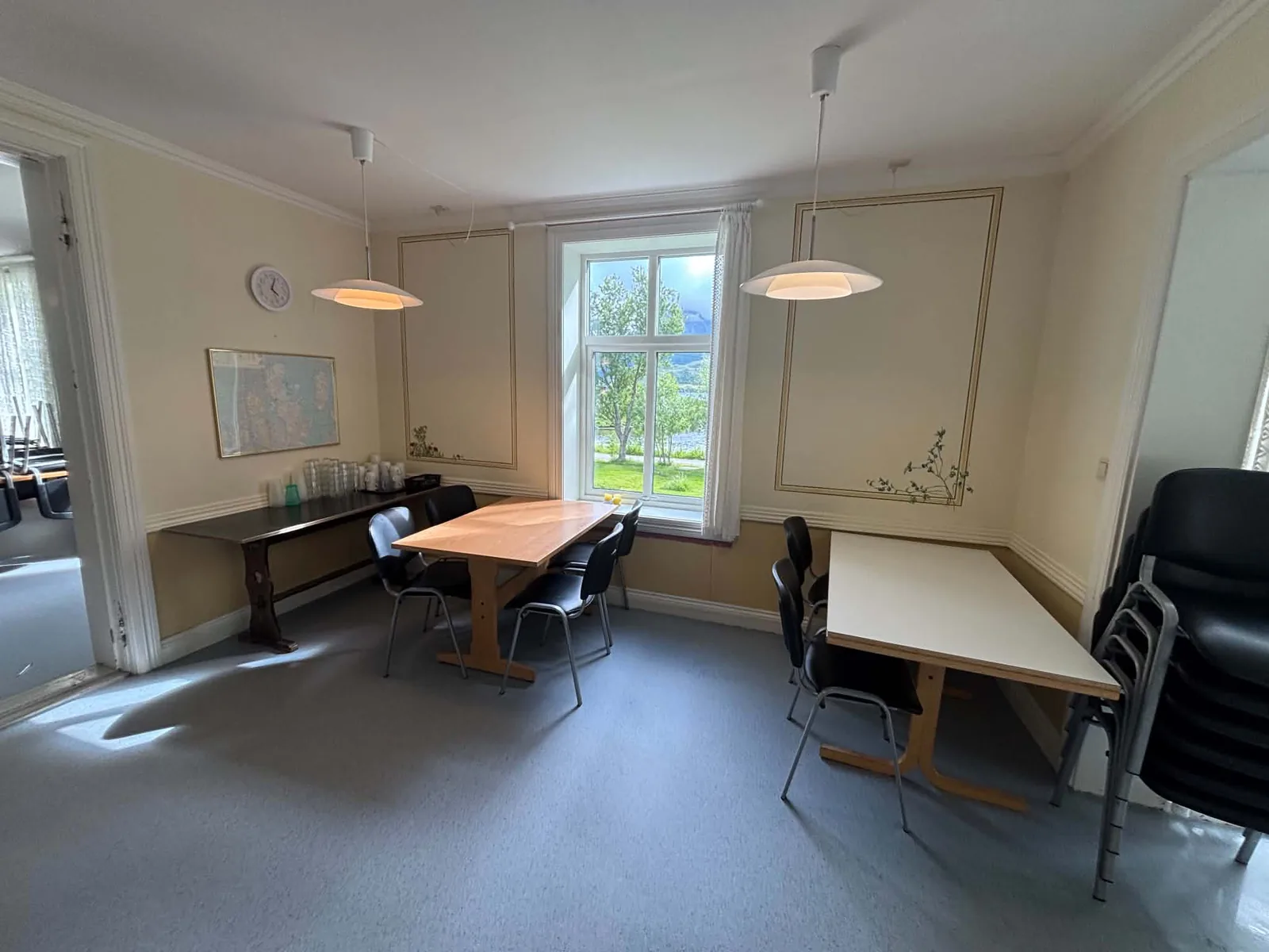 Lyst rom med langbord og vinduer på to sider