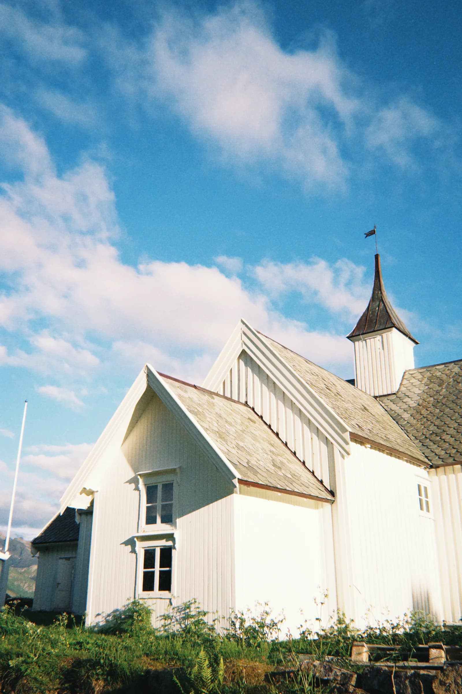 Øksnes kirke i kveldssol med blå himmel
