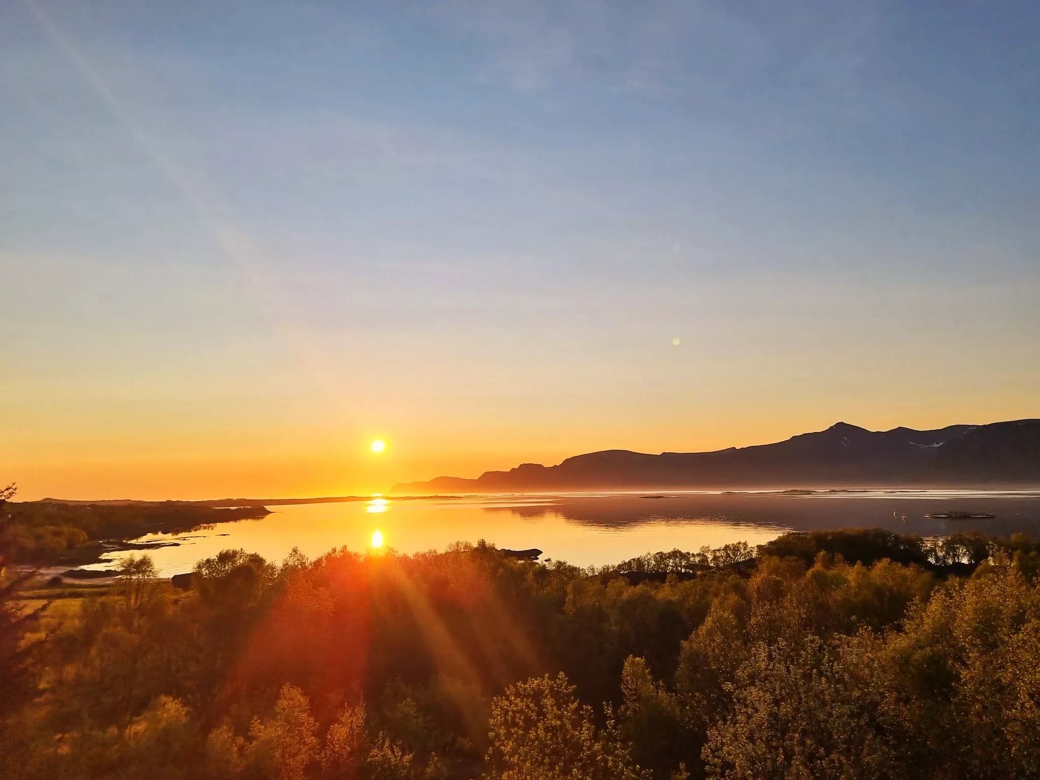 Lav kveldssol over fjorden med Vesterålsfjell i silhuett